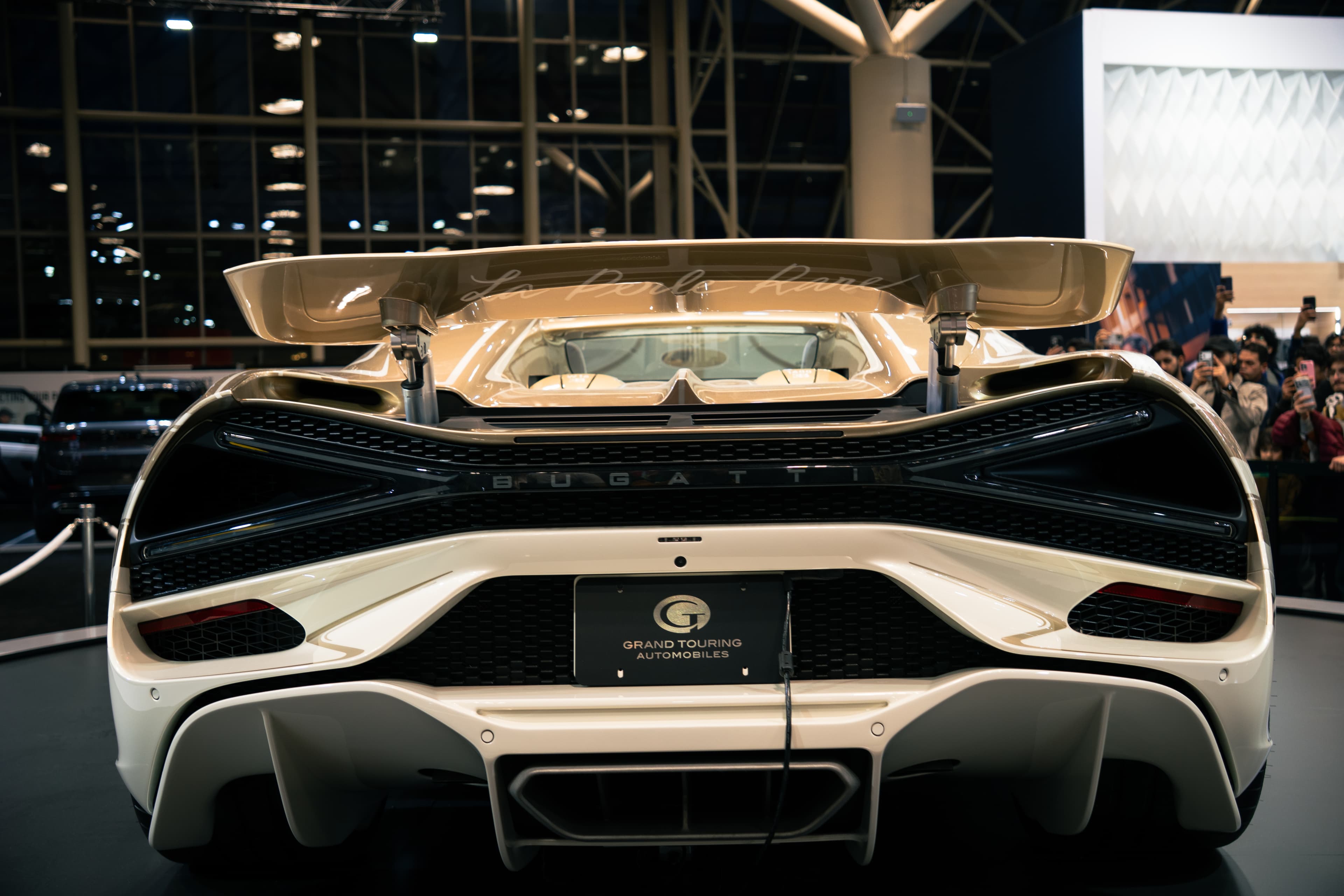 Rear view of a Bugatti displayed at an indoor automotive show